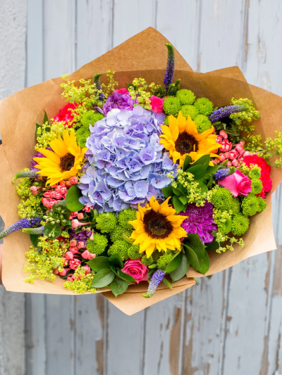 Moody Blue - Someone is going to love this gift. The kaleidoscope of vibrant colour ensures this striking hand-tied takes centre stage right away. With roses, hydrangeas and sunflowers this is certainly the right choice of gift to make a lasting impression.

The image shows Large Size

Please note: for seasonal and other supply reasons, we may occasionally substitute some of the blooms shown in the image. We will always try to be true to the bouquet's colour coordination, style, and shape and guarantee to give you the full value paid. If you have any queries, please email or call us and we would be delighted to confirm availability and explain alternatives. See the 'Contact Us' section.